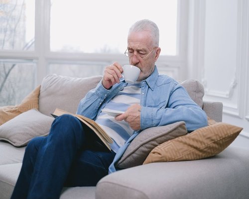 A person resting with a book and a cup of tea in a quiet room