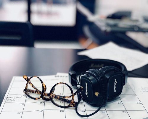Headphones lying on a desk beside an open planner